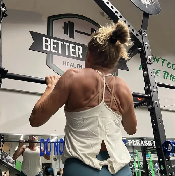 A member pulling her chin over the bar on a set of pull-ups at the rig.